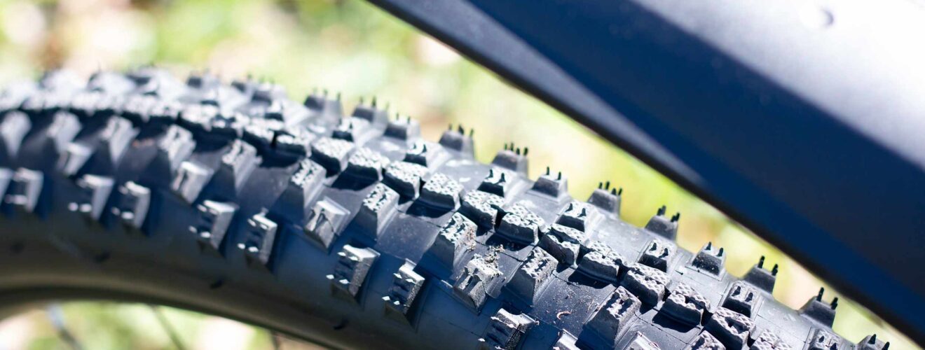 Nahaufnahme eines Mountainbike-Reifens mit grobem Stollenprofil für maximalen Grip im Gelände.