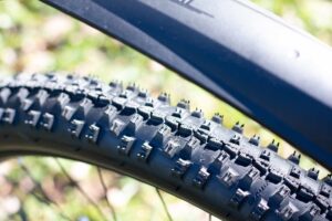 Nahaufnahme eines Mountainbike-Reifens mit grobem Stollenprofil f&uuml;r maximalen Grip im Gel&auml;nde.