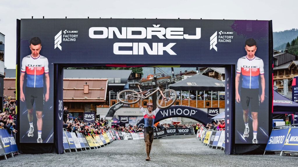 Ondřej Cink jubelt mit hochgehobenem Mountainbike im Ziel des UCI MTB World Cups in Leogang 2025 nach seinem ersten Elite-Weltcupsieg