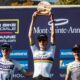 Finn Treudler jubelt beim Cube Factory Racing Saisonfinale 2025 in Mont-Sainte-Anne mit der Trophäe in den Händen, flankiert von dem Zweit- und Drittplatzierten auf dem Podium.