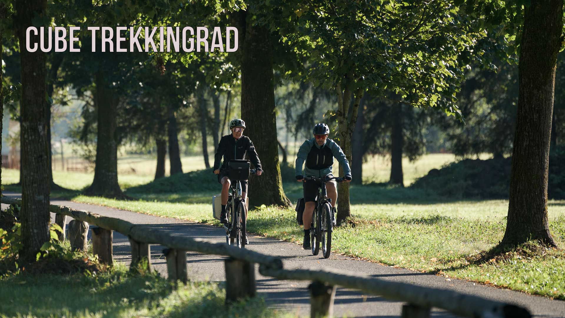 Zu sehen ist ein Bild mit der Aufschrift Cube Trekkingrad, auf der Abbildung fährt ein Paar, auf einem Radweg, durch einen Park.