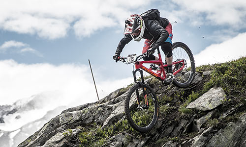 Downhill-Radfahrer mit Fullface-Helm fährt, über Felsen, einen steinigen Berg hinunter.