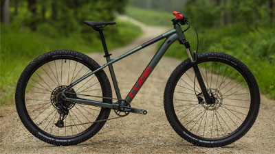 Zu sehen ist ein graues Cube Mountainbike mit roten Details, auf einem Schotterweg.